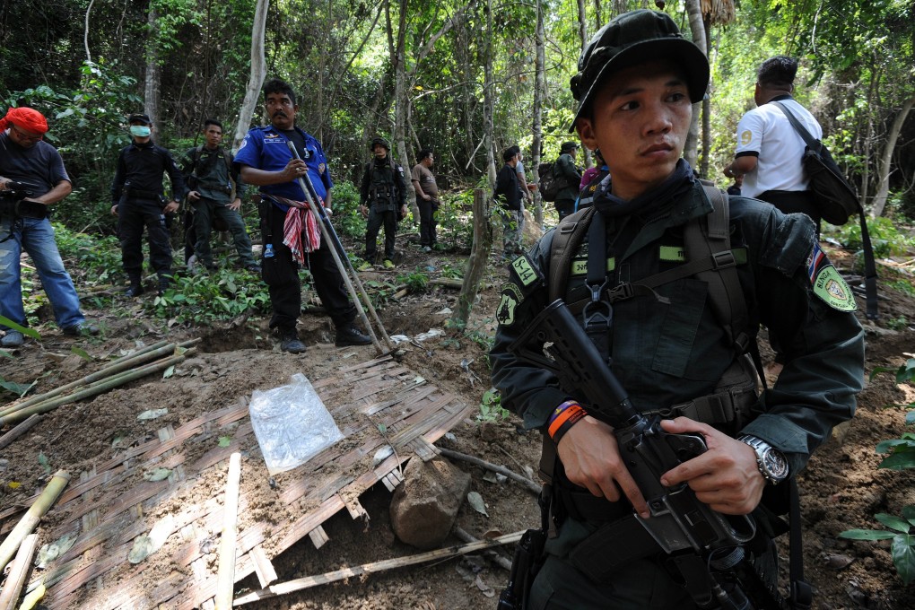 Soldiers stand guard as officials dig out skeletons from shallow graves at an abandoned jungle camp in Thailand's southern Songkhla province bordering Malaysia. Photo: AFP