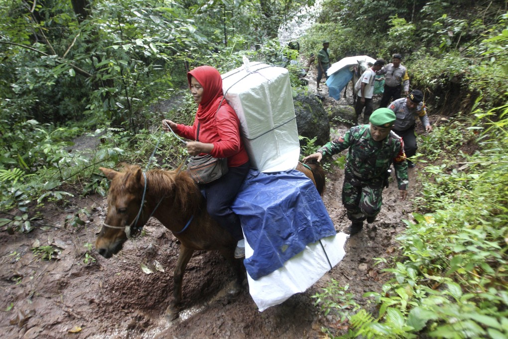 Police officers and soldiers escort electoral workers using horses to distribute ballot boxes and other election paraphernalia to polling stations in remote villages in Tempurejo, East Java. Photo: AP