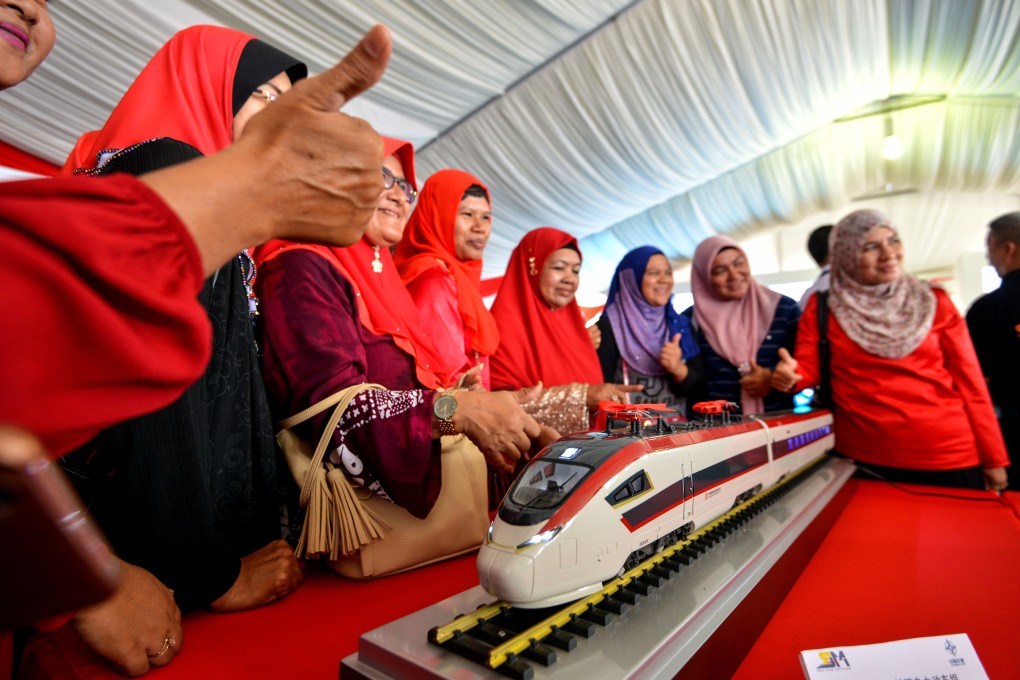 People pose with a model train for the East Coast Rail Link project. Photo: Xinhua