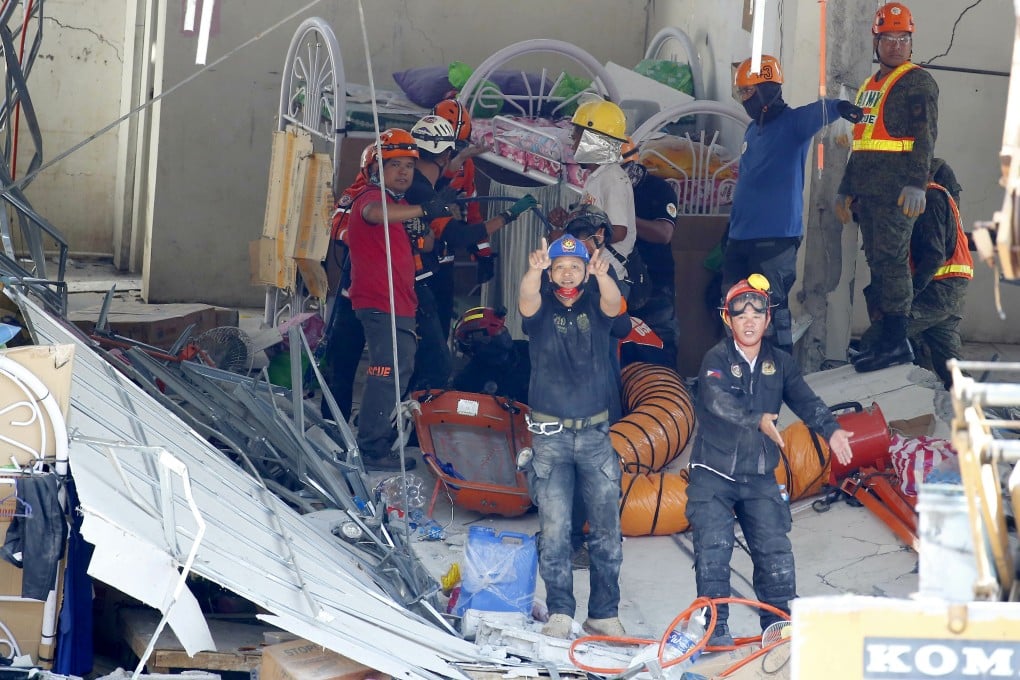 Rescuers gesture to clear the way following the discovery of a survivor in a collapsed commercial building in Porac, Pampanga province. Photo: AP