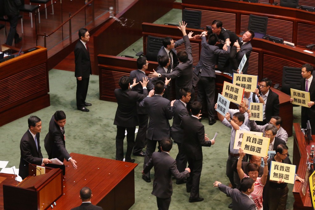 On July 3, 2014, lawmaker Wong Yuk-man (top) threw a glass and documents at chief executive Leung Chun-ying during a question-and-answer session in the Legislative Council. Divisive politics in Hong Kong predated the divisive Occupy protests that would start in September 2014. Photo: K.Y. Cheng