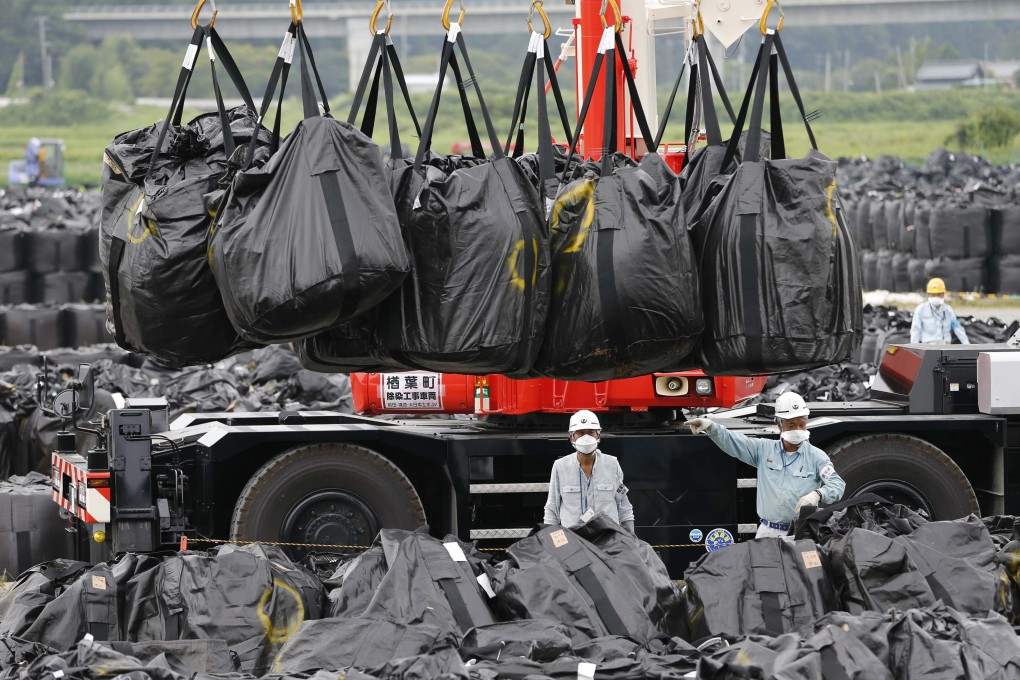 Workers move waste containing radiated soil, leaves and debris from the decontamination operation at a storage site in Naraha town. Photo: Reuters