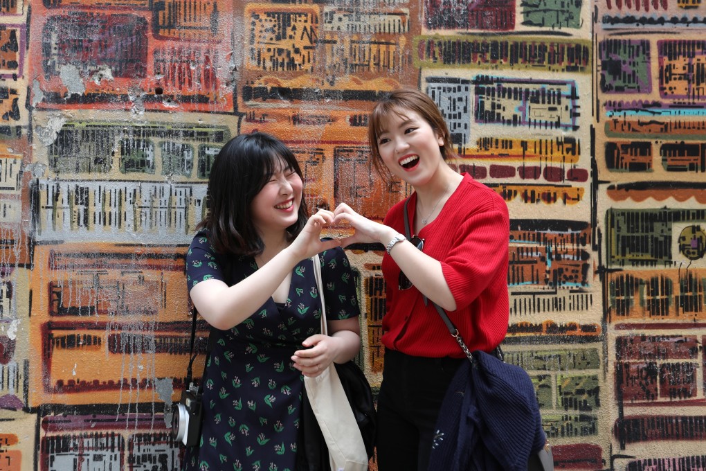 Cosmetic researchers from South Korea Sun Woo (left), 26, and So Yeon, 26, take pictures against the popular graffiti wall on Graham Street in Central. Photo: Nora Tam