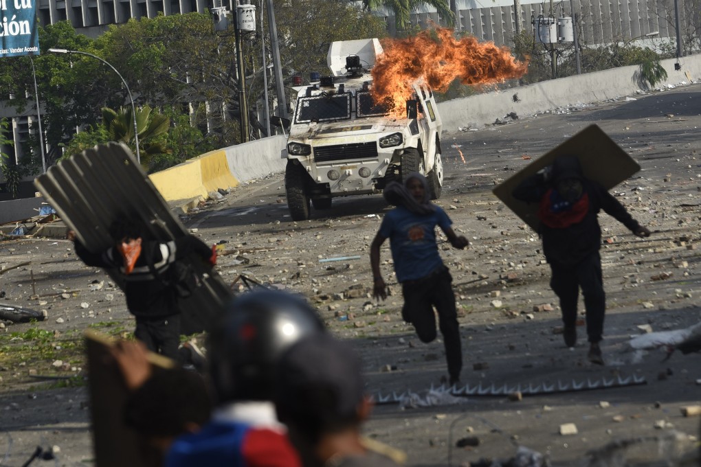 Flames and smoke rise from an armored vehicle during clashes between protesters and members of the National Bolivarian Armed Forces after an attempted military uprising on Francisco Fajardo Highway in Altamira, Caracas. Photo: Bloomberg
