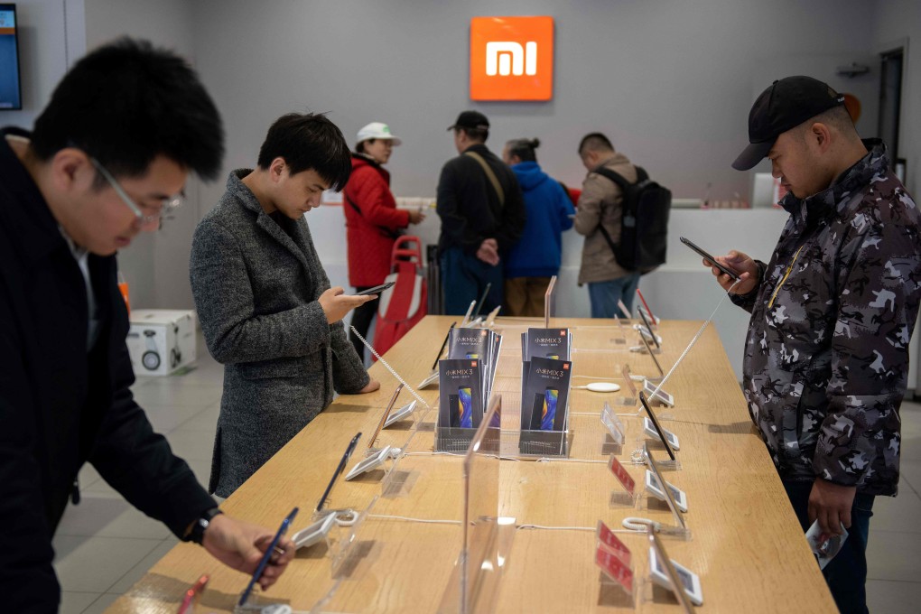 Customers look at mobile phones in a Xiaomi shop in Beijing on November 7, 2018. Photo: AFP