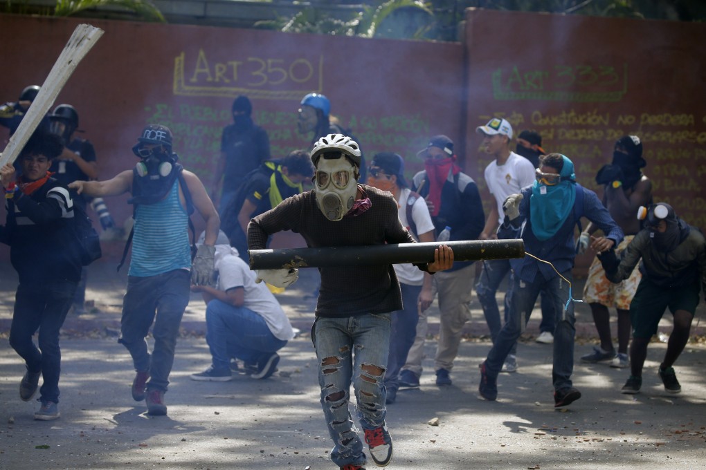 Anti-government protesters, one carrying a home made mortar, take cover as security forces fire tear gas to disperse demonstrators in Caracas on May 1. Photo: AP