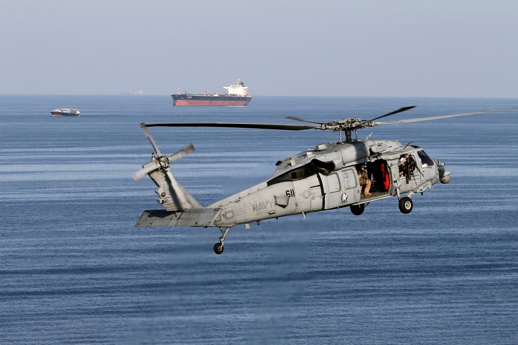 An MH-60S helicopter hovers in the air with an oil tanker in the background as the USS John C. Stennis makes its way to the Gulf through the Strait of Hormuz. Photo: Reuters