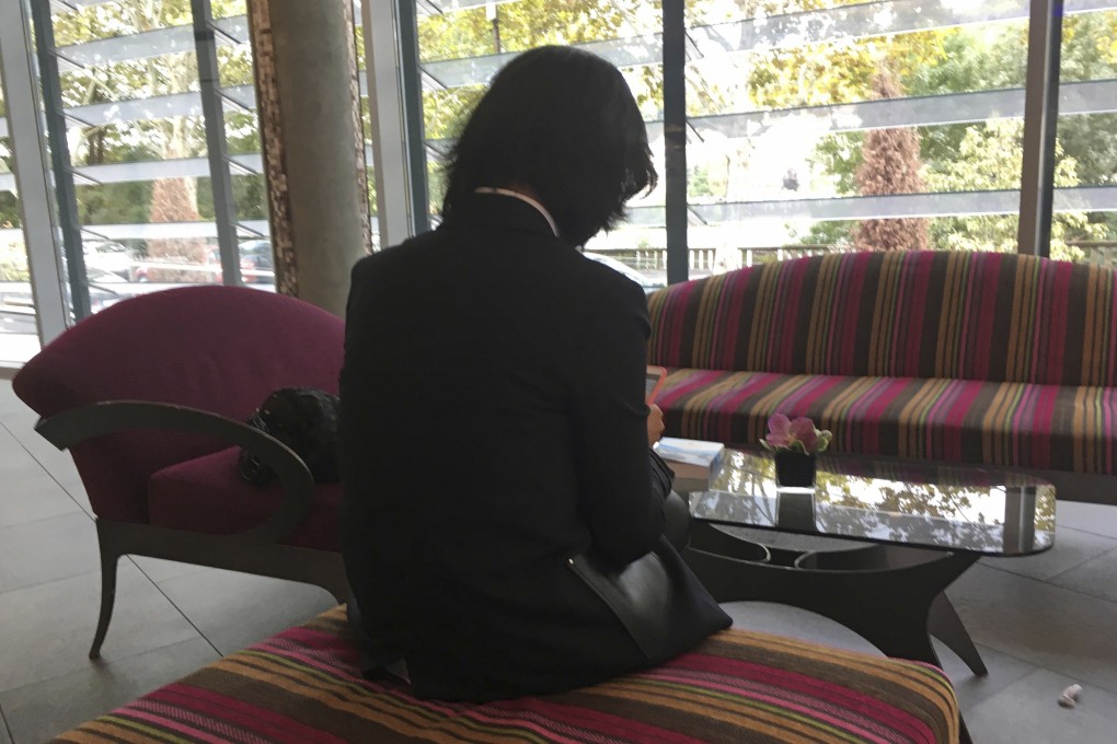 Grace Meng, who does not want her face shown, looks at her mobile phone in the lobby of a hotel in Lyon, France, in October. Photo: AP