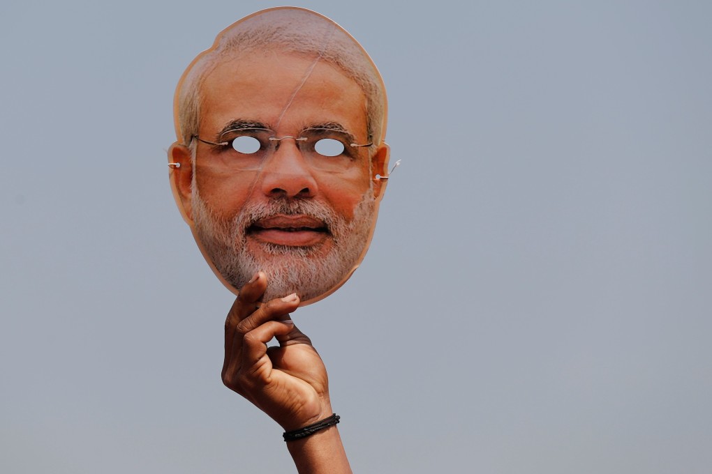 A supporter of India’s ruling Bharatiya Janata Party holds a mask of Prime Minister Narendra Modi during an election campaign rally at Meerut in Uttar Pradesh. Photo: Reuters
