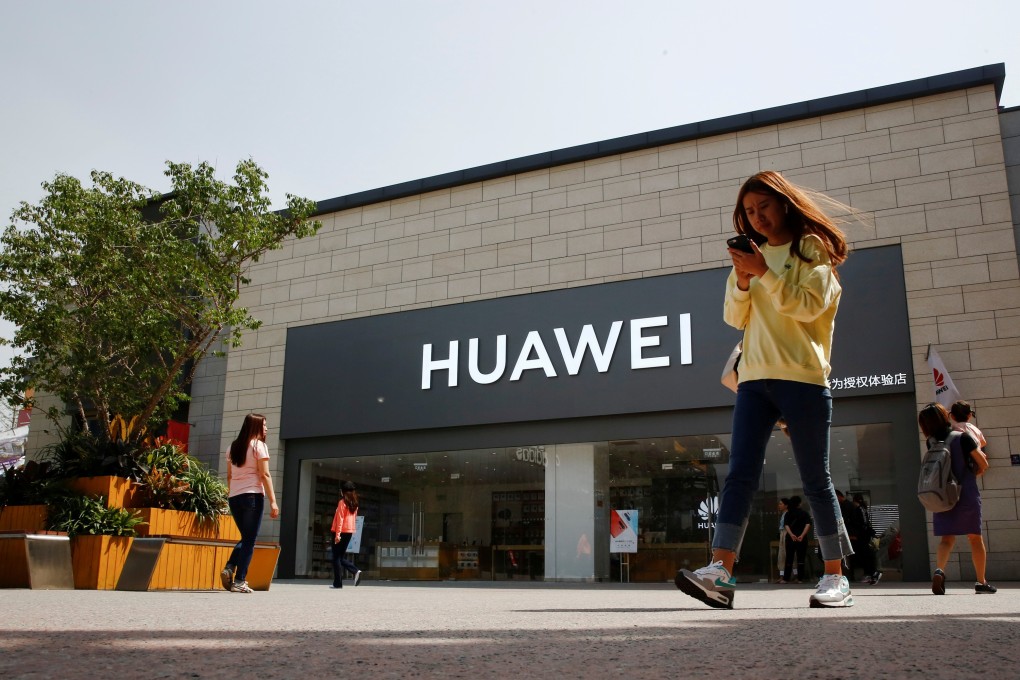 A woman looks at her phone as she walks past a Huawei shop in Beijing. Photo: Reuters