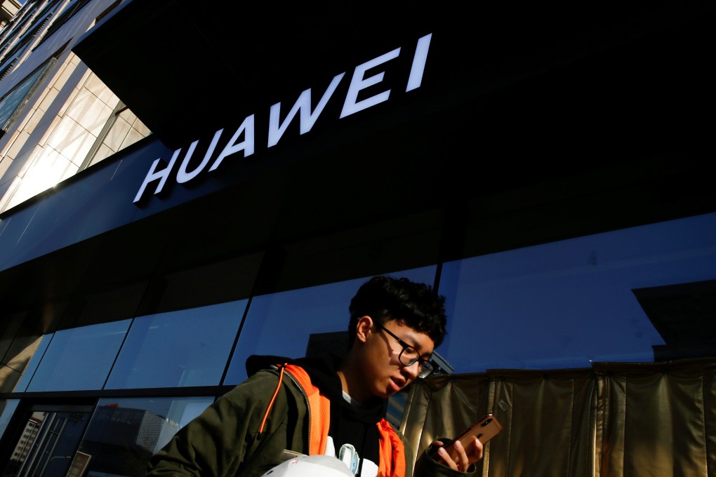 A man uses his phone as he walks past a Huawei shop in Beijing in December. Photo: Reuters