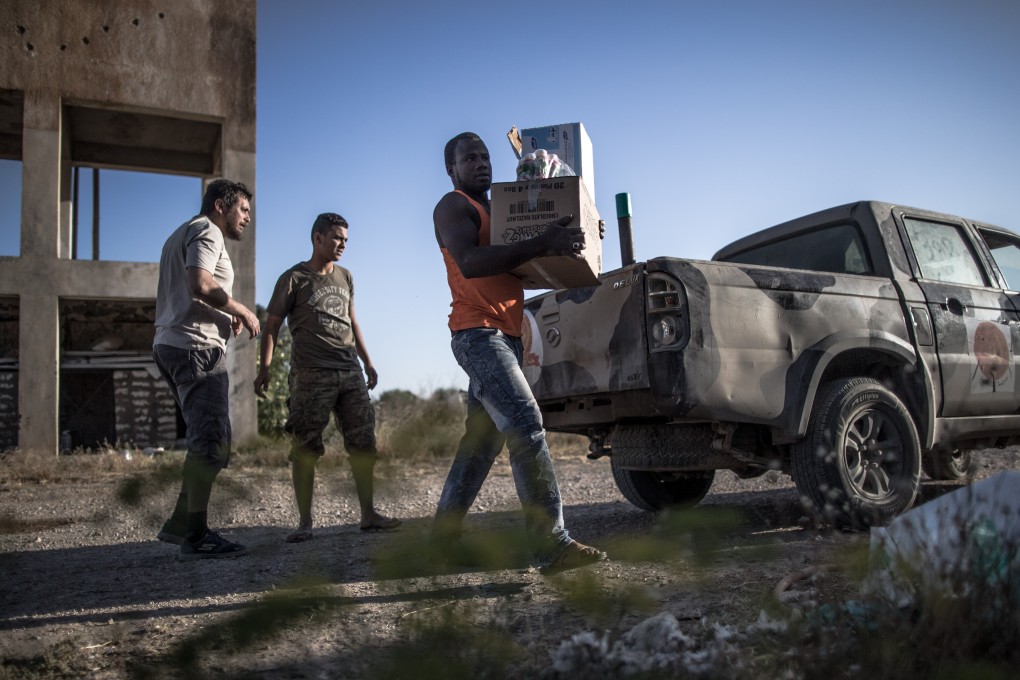 Fighters from UN-backed government forces distribute food and aid to people trapped near the al-Sawani frontline in Tripoli. Photo: Xinhua