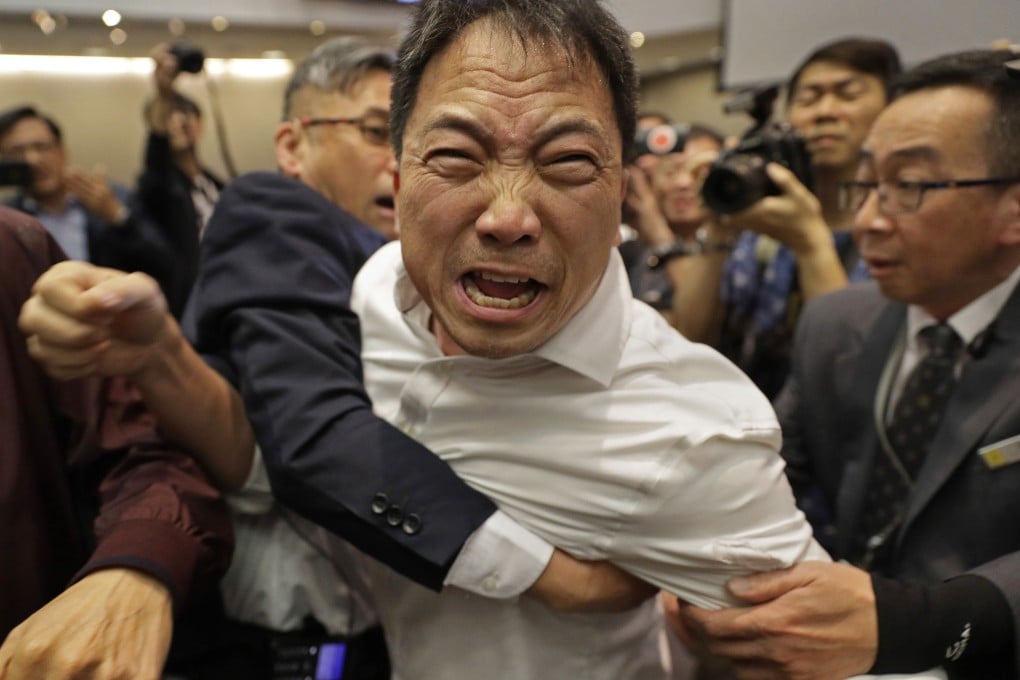 Pro-democracy lawmaker Wu Chi-wai, center, scuffles with security guards at the Legislative Council on May 11. Photo: AP
