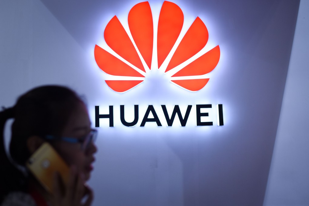 A woman uses her mobile phone in front of a Huawei logo at the Beijing International Consumer Electronics Expo in July 2018. Photo: AFP