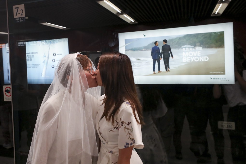 Cleo Lo (left) and Kitty Choi share a kiss in front of the Cathay Pacific advert displayed in Hong Kong’s Central station. Photo: Sam Tsang