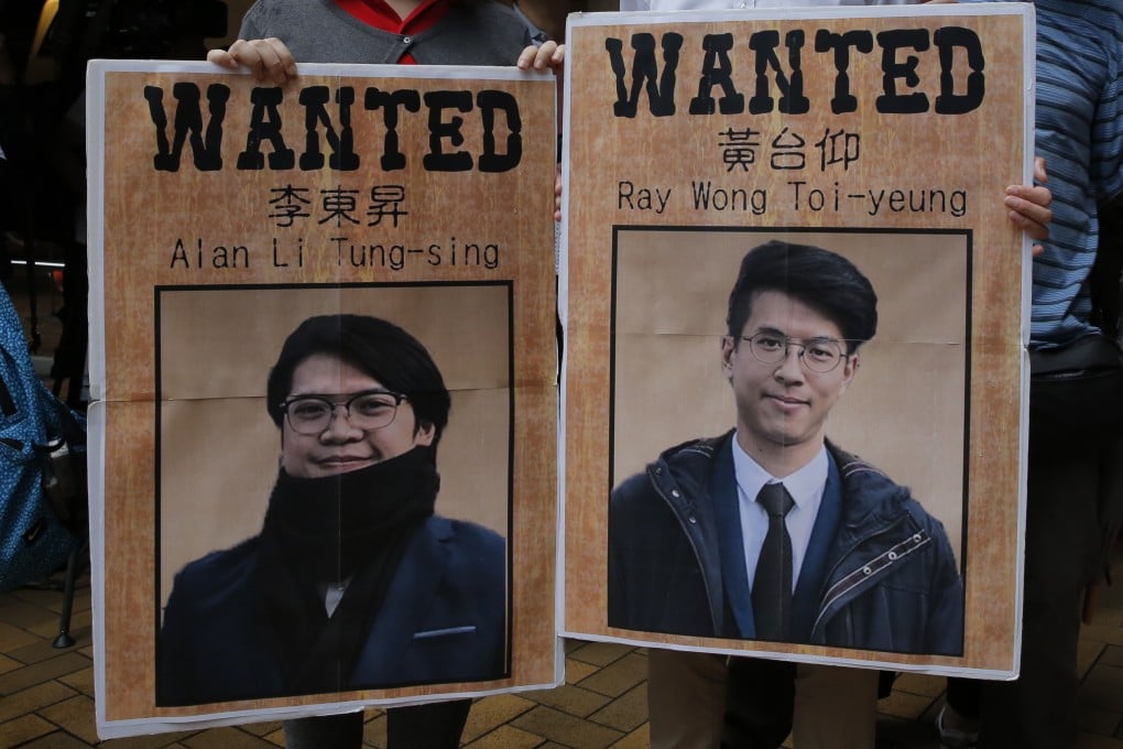 Pro-government demonstrators hold up posters of Hong Kong activists Alan Li and Ray Wong, who have been granted asylum in Germany, at a rally in the city on May 23. Photo: AP