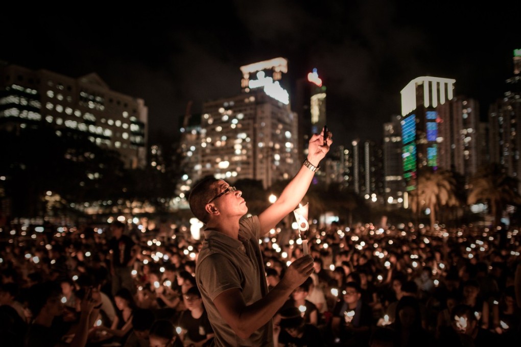 A man takes a picture with his mobile phone as people hold candles to commemorate China's 1989 Tiananmen Square events during a candlelight vigil in Hong Kong on June 4, 2014. Up to 200,000 people were set to take part in a candlelight vigil in Hong Kong on June 4 to commemorate the 25th anniversary of the bloody Tiananmen Square crackdown, as China seeks to wipe the incident from memory. AFP PHOTO / Philippe Lopez