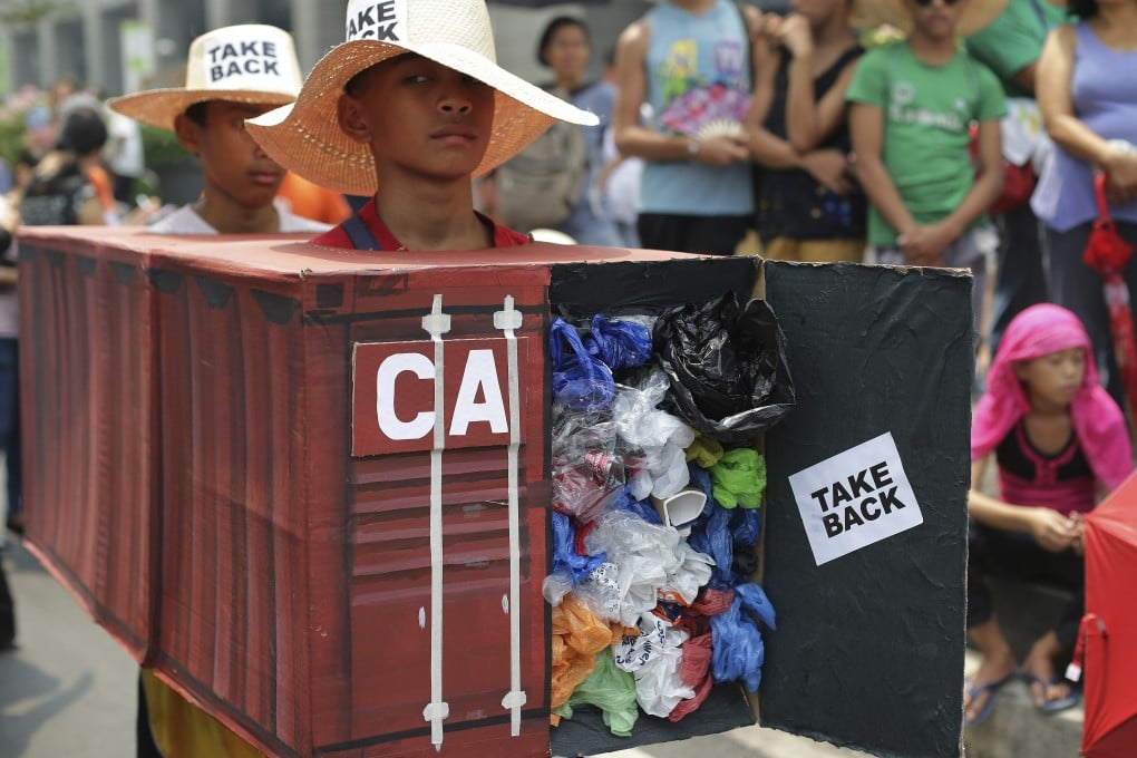 Filipino environmental activists in the financial district of Makati wear a mock container filled with garbage in 2015 to symbolise the containers of waste that were shipped from Canada to the Philippines. Photo: AP