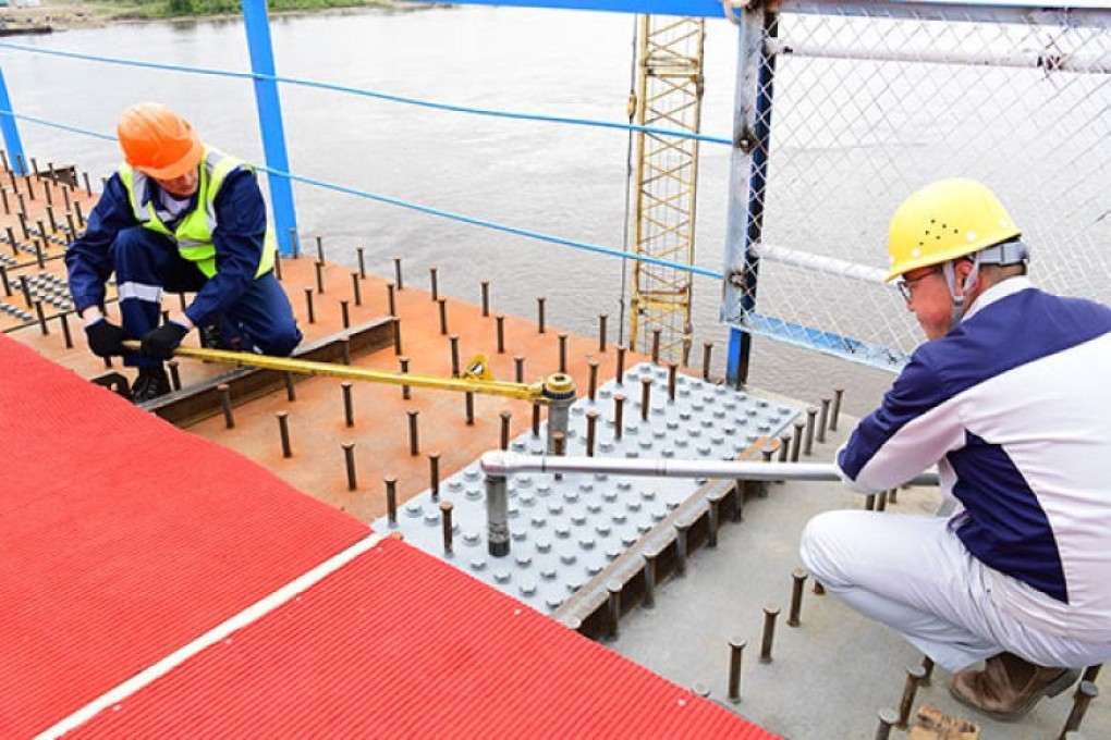 Construction workers fasten bolts to join two sections of a bridge over the Heilongjiang River between China and Russia. Photo: Xinhua