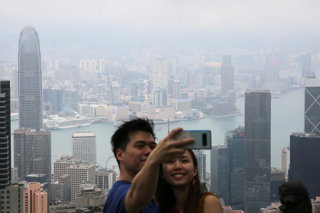 A couple pose for a selfie from The Peak flanked by Victoria Harbour and the downtown Hong Kong skyline on April 19. Photo: Sam Tsang