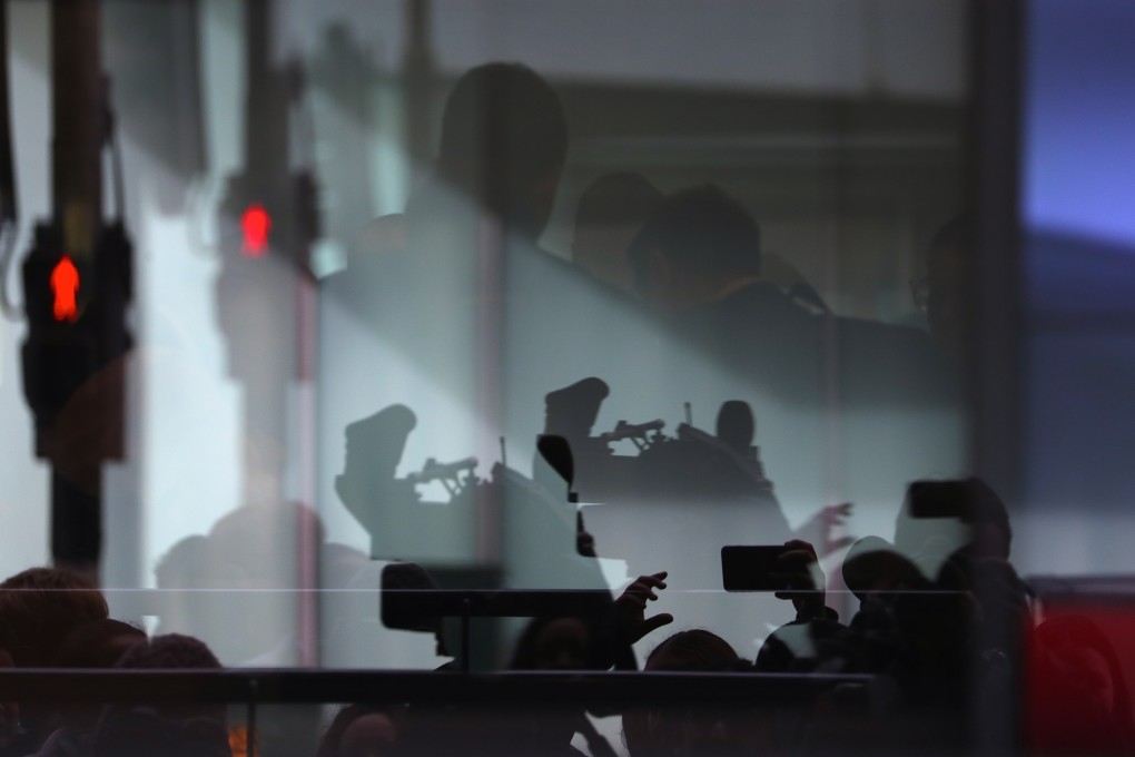 Members of the media and security staff reflected in a window at the main entrance to the ABC building in Sydney. Photo: EPA