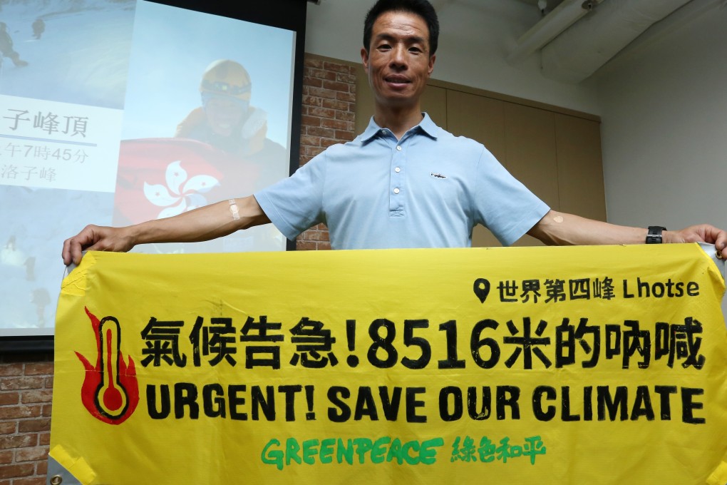Climber Wong Wai-kin displays a Greenpeace banner to save the environment while sharing his climbing experience. Photo: Jonathan Wong