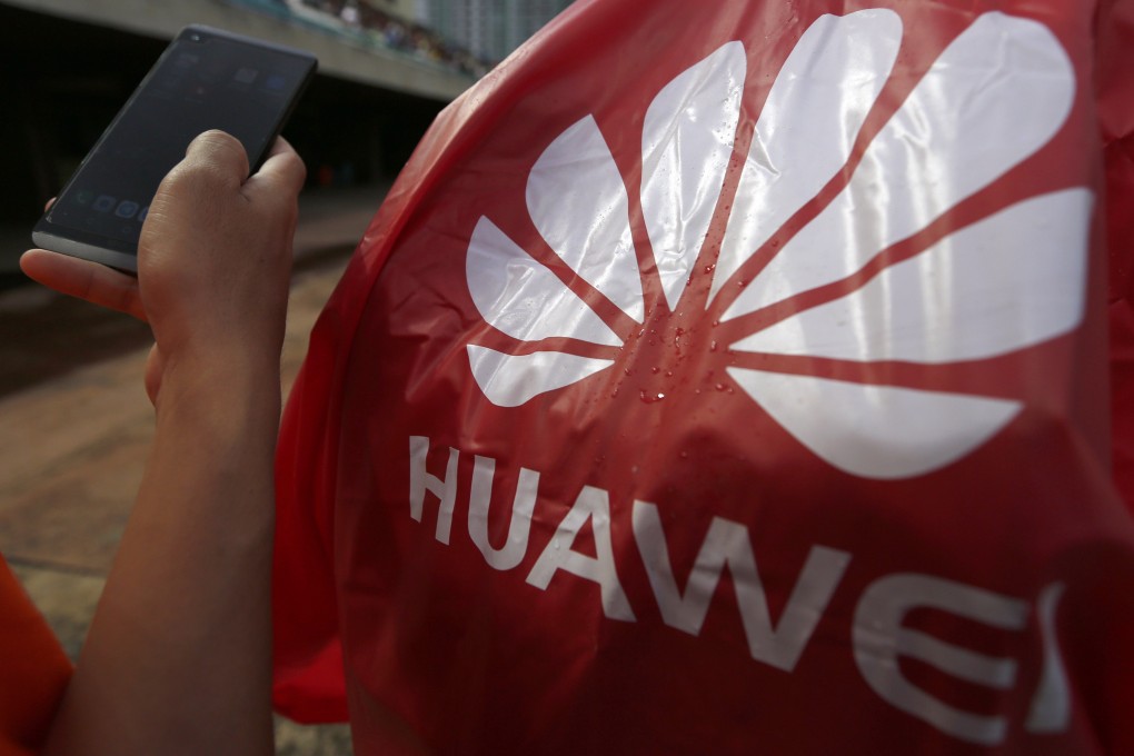 A Cambodian man play his smartphone near Huawei logo in Phnom Penh. Photo: EPA-EFE