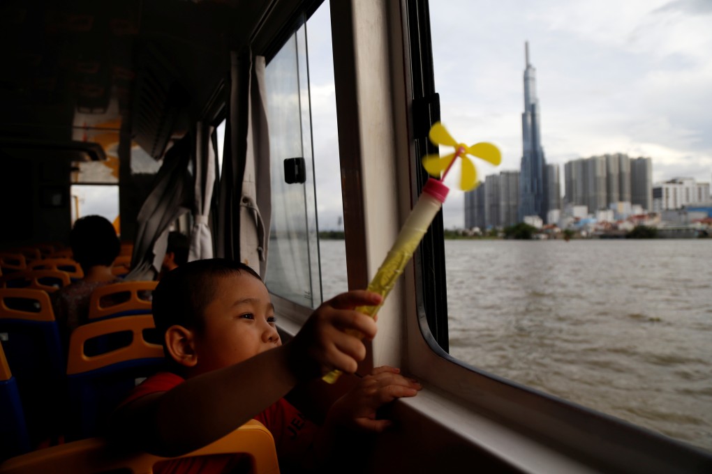 A a child on a Saigon waterbus brandishes a pinwheel as he passes Landmark 81, Vietnam’s tallest building, in Ho Chi Minh City on June 6. While Vietnam has enormous potential for wind and solar power generation, funding for coal-power electricity plants under China’s Belt and Road Initiative could derail its renewable energy push. Photo: Reuters