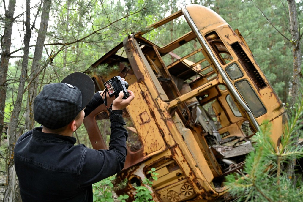 A visitor takes a picture of the wreckage of a bus in the ghost city of Pripyat during a tour in the Chernobyl exclusion zone. Photo: AFP