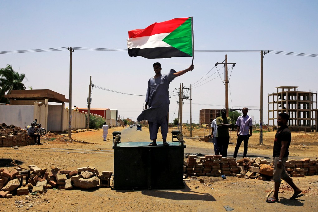 A Sudanese protester holds a national flag as he stands on a barricade along a street in Khartoum on June 5. Photo: Reuters