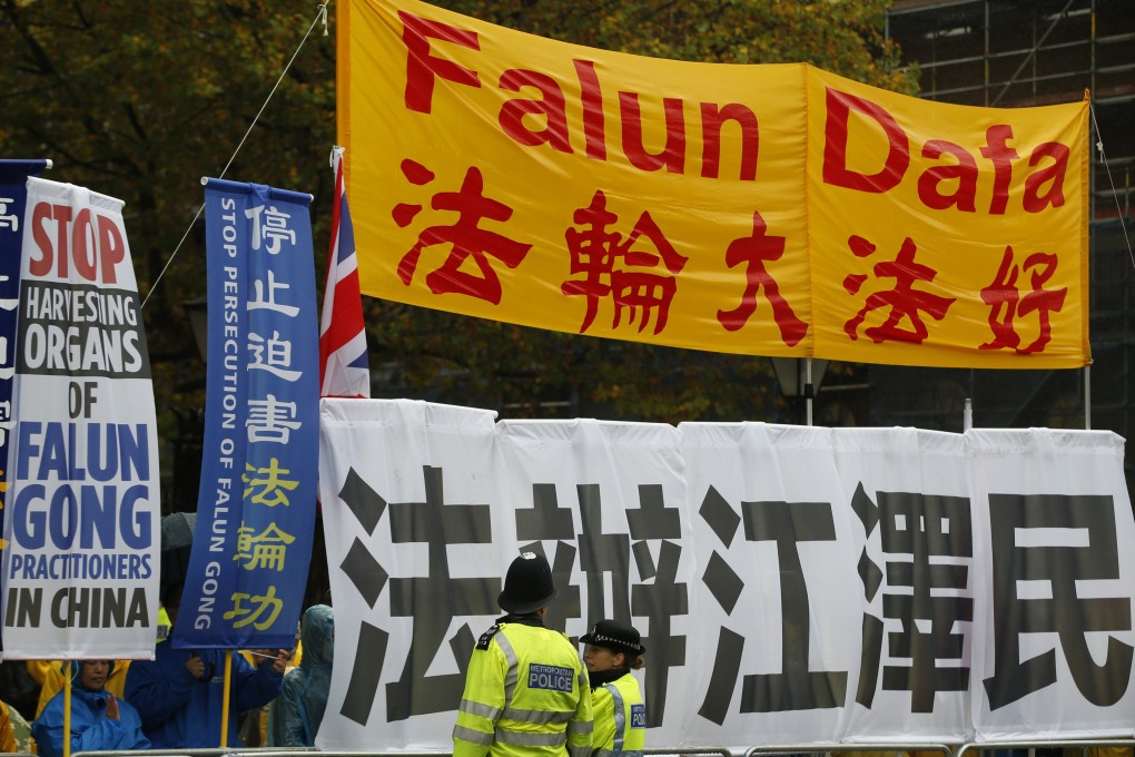 Two police officers stand guard in front of Falun Gong supporters as they protest outside Downing Street ahead of the arrival of Chinese President Xi Jinping in London in October 2015. Photo: AP