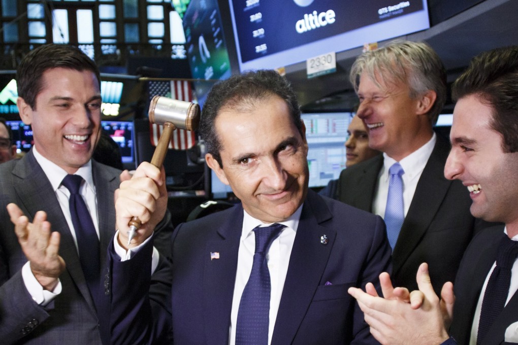 Patrick Drahi (centre) pretends to hit himself on the head with a mallet during the initial public offering of his telecommunications company on the New York Stock Exchange. He has offered to buy auctioneer Sotheby’s in a US$3.7 billion deal that would see its shares delisted from the exchange. Photo: EPA-EFE