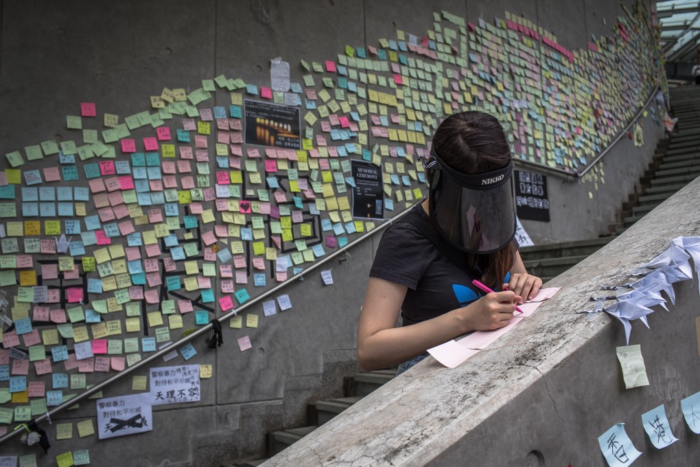 A woman writes a message next to anti-extradition notes taped to a wall near the Legislative Council in Hong Kong. Executive councillors’ misreading of public opinion might have hurt the Carrie Lam administration and “one country, two systems”. Photo: EPA-EFE