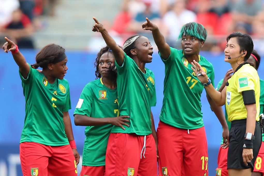 Cameroon players argue with referee Qin Liang. Photo: EPA