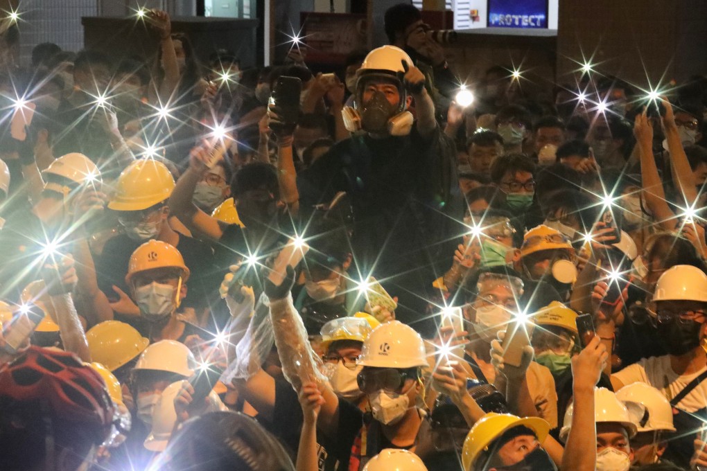 Anti-extradition bill protesters turn on their mobile phone torches as they gather outside police headquarters in Wan Chai on June 21. Photo: Felix Wong