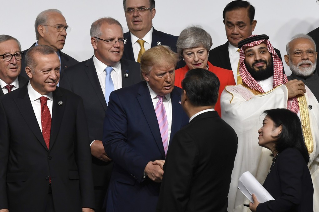US President Donald Trump (centre) shakes hands with his Chinese counterpart Xi Jinping before a group photo at the G20 summit in Osaka on Friday. Photo: AP