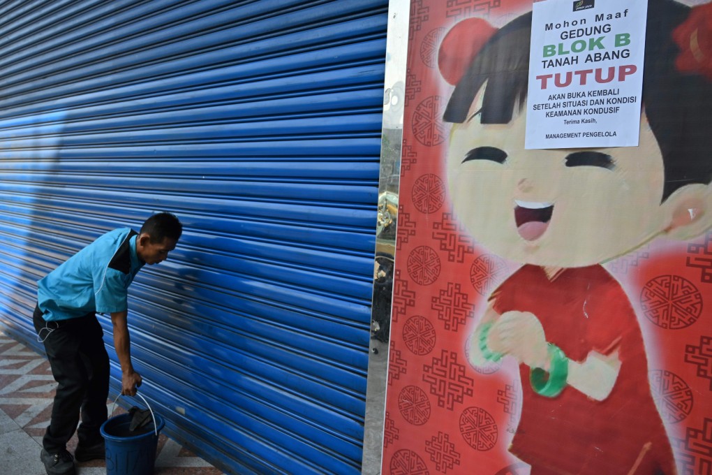 An Indonesian worker cleans the door of a market closed due to protests over the Indonesian election result. Photo: AFP