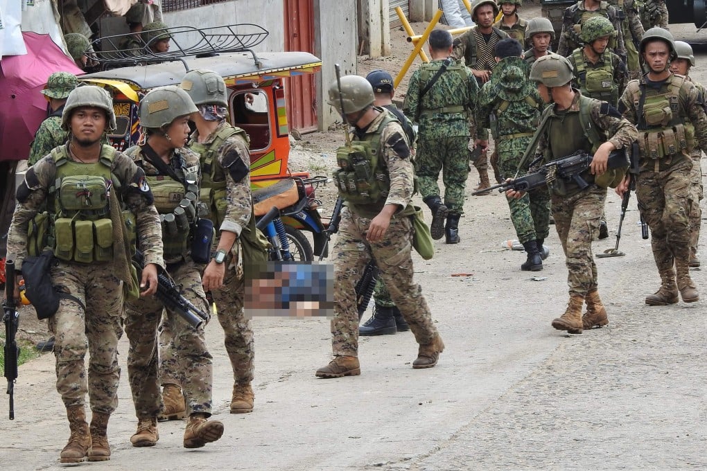 Soldiers walk past the body of a man killed in an attack on Jolo island on Friday. Photo: AFP