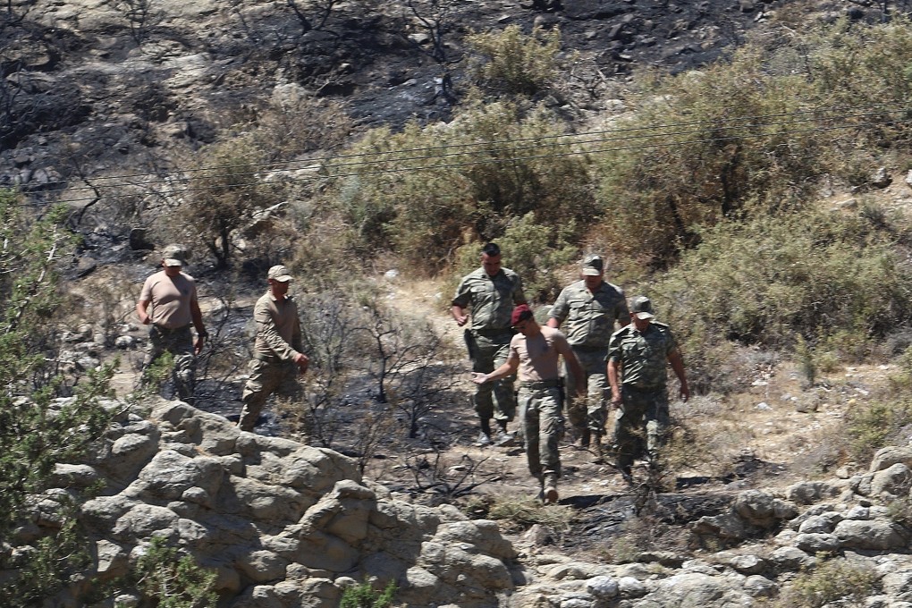 Military personnel walk on a slope near where the missile struck in northern Cyprus. Photo: Reuters