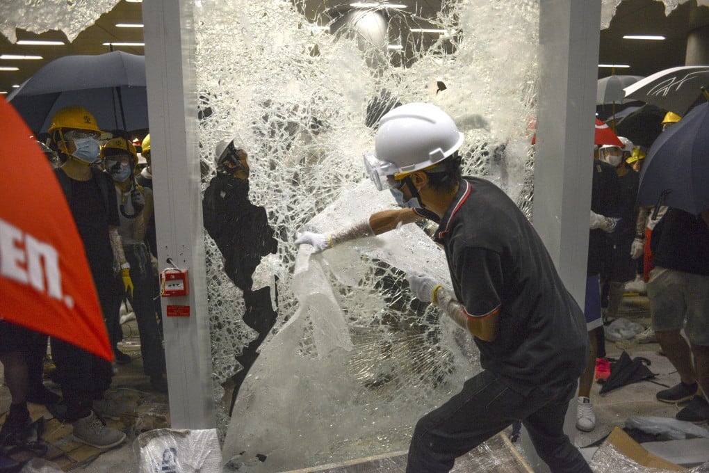 A protester breaks a glass door at the Legislative Council building on Monday. Photo: Antony Dickson