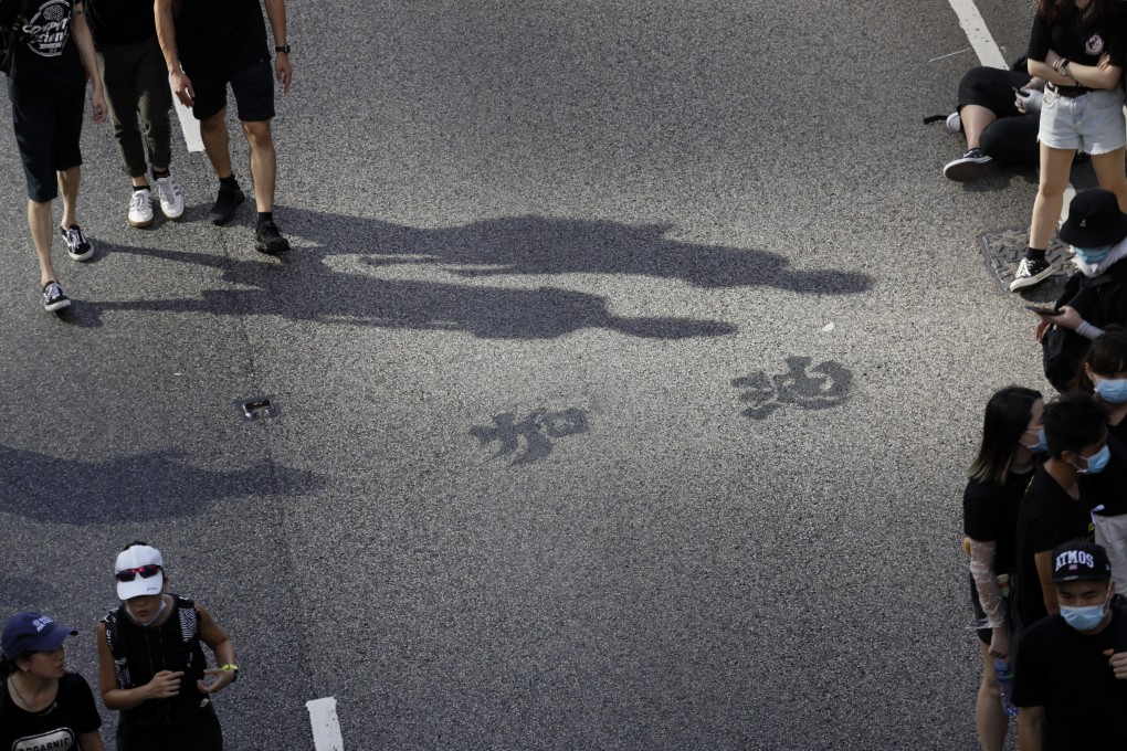 Chinese characters reading “add oil” from one angle and “Hong Kong” from another are displayed on a road during a protest in Hong Kong on July 1. Both the Hong Kong and Beijing governments should see that continued unrest is in nobody’s interests. Photo: Bloomberg