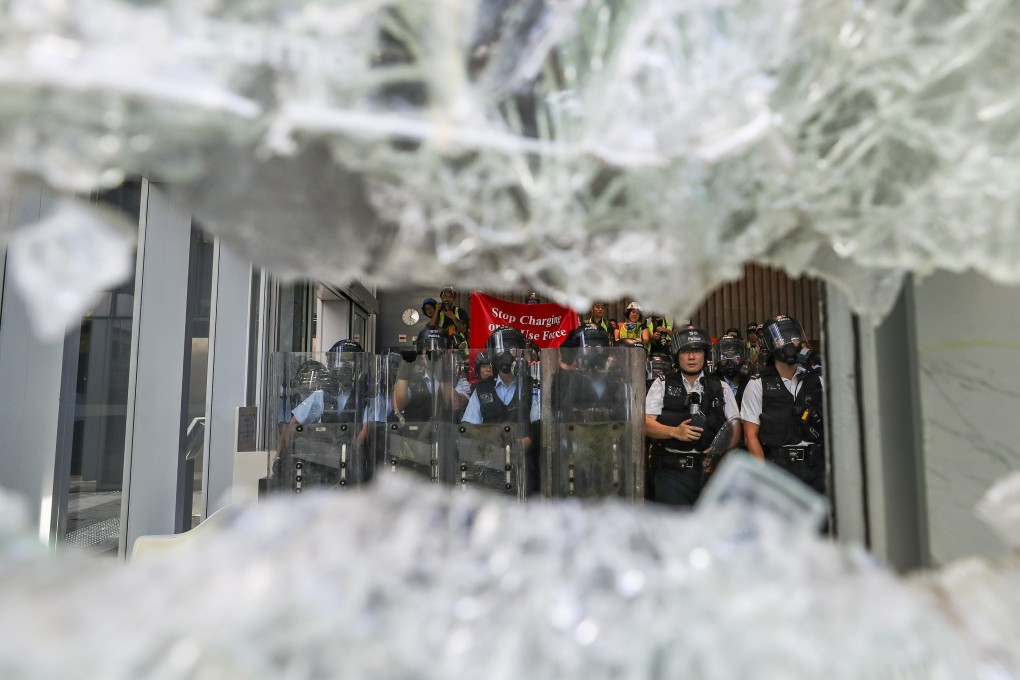 Riot police stand guard on Monday as protesters smash windows of the Legislative Council complex in Tamar. Photo: Sam Tsang