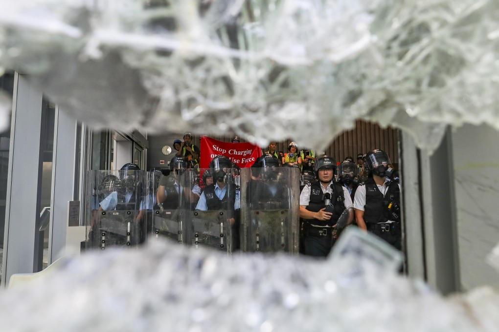 Riot police watch as crowds smash the doors of the Legislative Council. Photo: Sam Tsang
