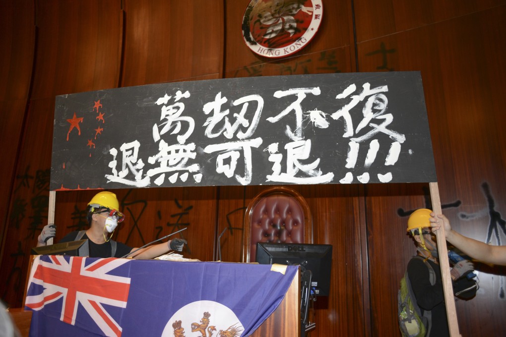 Protesters who stormed the main chamber of the Legislative Council drape the colonial flag over the podium during their protest against the extradition bill on July 1. Photo: Antony Dickson