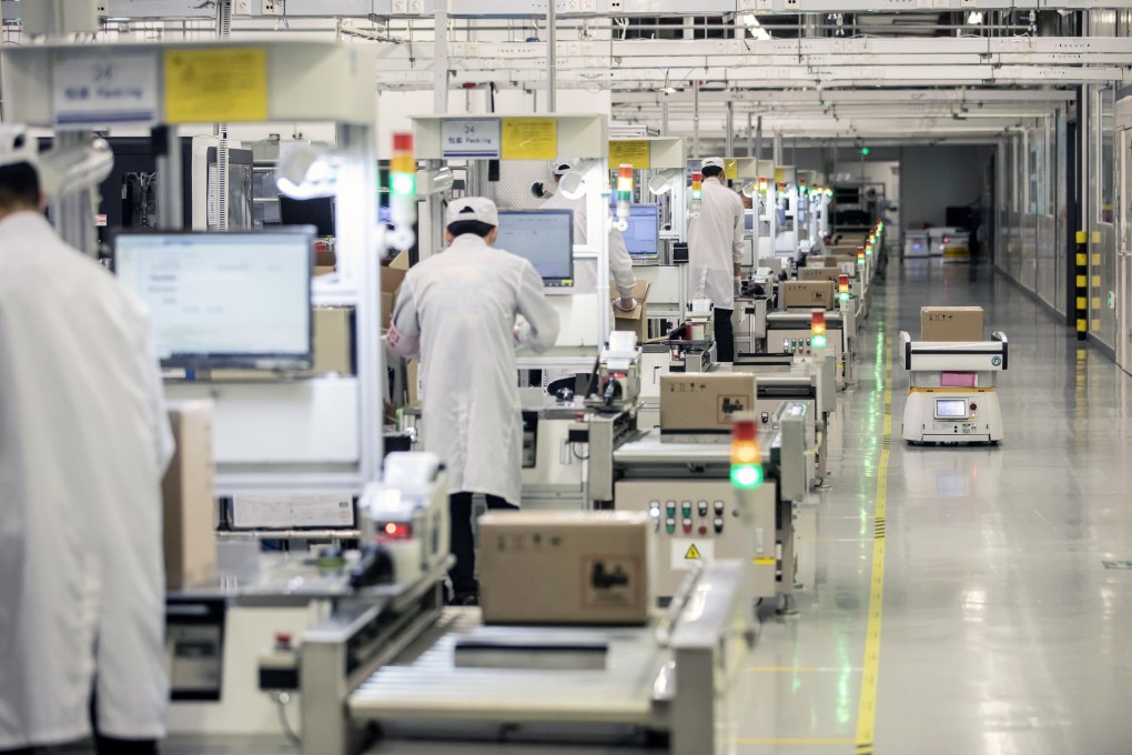 A robot passes employees working on a mobile phone assembly line at a Huawei Technologies Co. production base in Dongguan. Photo: Bloomberg