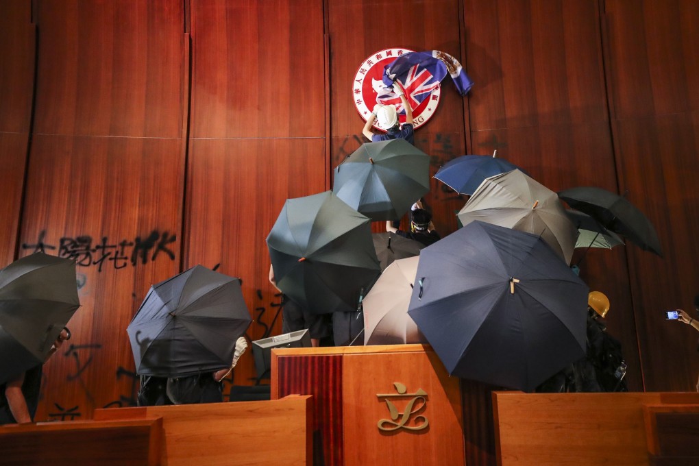 A protester covers the Hong Kong Special Administrative Region emblem with a British colonial flag during the storming of the Legco complex. Photo: Sam Tsang