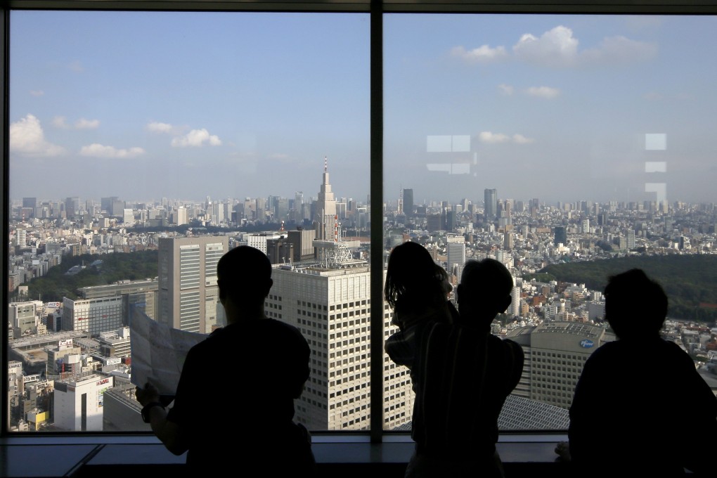 A family looks out of an office building window in central Tokyo. Photo: EPA