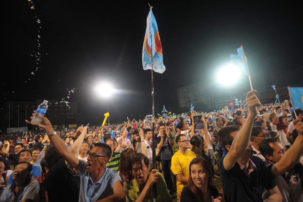 Workers’ Party supporters wave flags as they celebrate at Hougang stadium after the 2015 Singapore general election. Photo: AFP