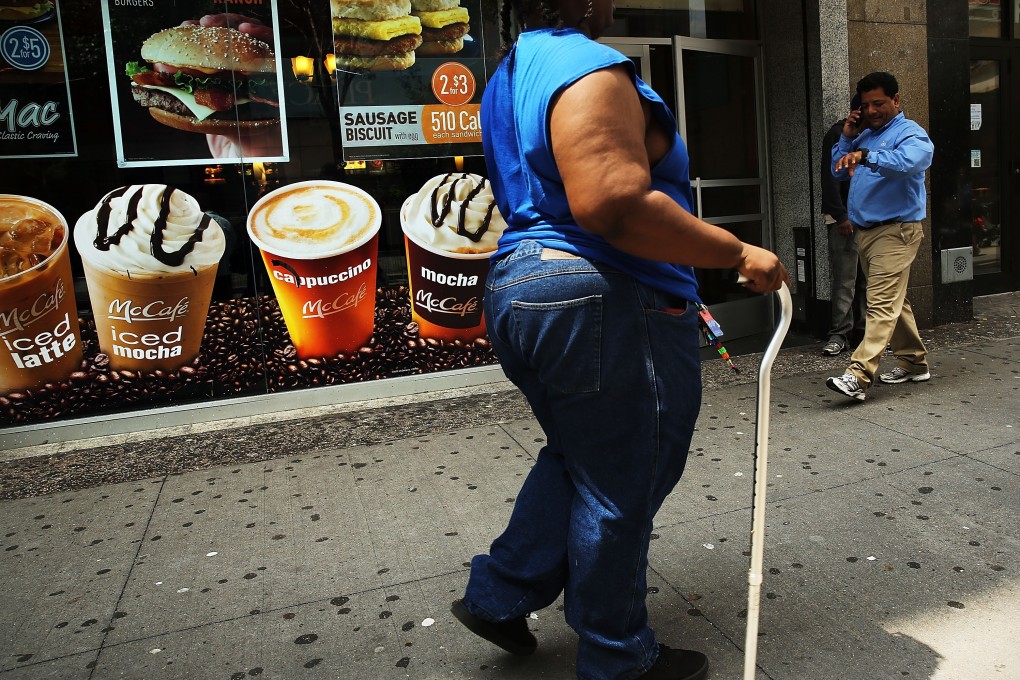 A woman walks past a sign advertising sugary drinks. Photo: AFP