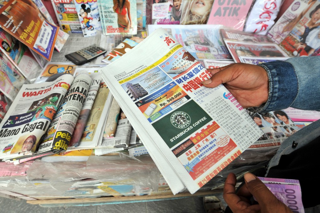 An Indonesian stallholder with a Chinese-language newspaper in Jakarta. Photo: AFP